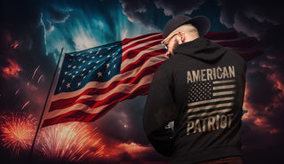 A vibrant firework display illuminates the background, highlighting a massive USA flag. In the foreground, a man dons a patriotic hoodie adorned with the USA flag, embodying the spirit of an American patriot."